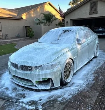 Soapy body panel being worked by hand during clay bar decontamination